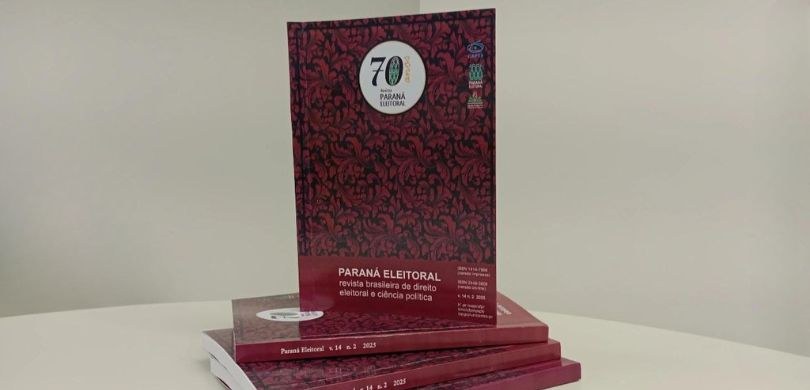 Revista Paraná Eleitoral lança edição comemorativa de 70 anos Fotografia de uma edição impressa comemorativa da Revista Eleitoral posicionada em pé sobre outr...