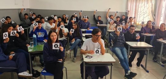 Fotografia de cinco pessoas, quatro homens e uma mulher, em uma sala clara. Dois rapazes com col...