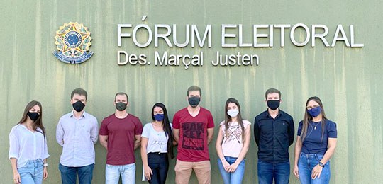 Fotografia de um grupo de pessoas em frente ao Fórum Eleitoral Des. Marçal Justen