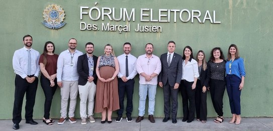foto registrada em frente ao Fórum Eleitoral da Lapa. Servidoras e servidores estão posando para...