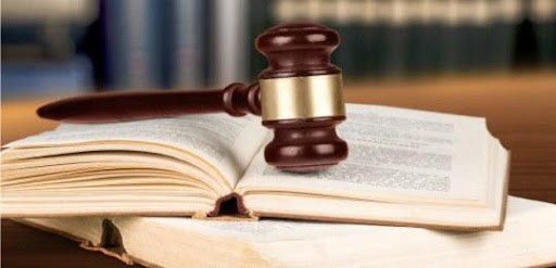 Fotografia de um malhete em cima de dois livros abertos.