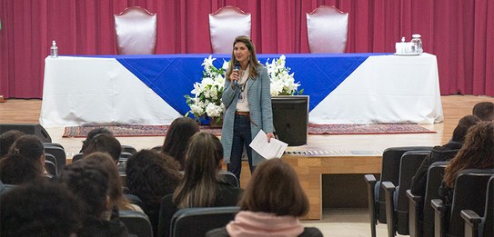 Fotografia de um homem falando em frente a um grupo de pessoas em um auditório. Ele usa uma blus...