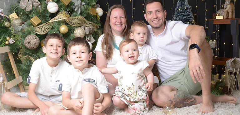 Servidoras da Justiça Eleitoral do Paraná falam da sua relação com a maternidade 2 Fotografia de uma mulher loira e um homem de cabelo castanho posando com seus quatro filhos, sen...