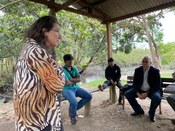 Fala de uma moça, com dois membros da tribo indígena sentados, junto ao presidente do TRE-PR.