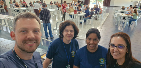 Fotografia de cinco pessoas, quatro homens e uma mulher, em uma sala clara. Dois rapazes com col...