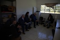 Um grupo de seis pessoas está sentado dentro de uma sala de paredes brancas. Duas pessoas estão ...