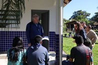 Um grupo de cinco pessoas está reunido ao ar livre, em frente a um prédio com azulejos azuis e b...