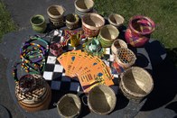 Uma variedade de cestos artesanais de palha e miçangas coloridas estão dispostos sobre uma mesa ...