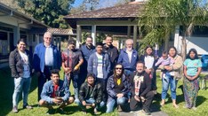 Uma foto de grupo de cerca de 13 pessoas, entre adultos e crianças, reunidas em um gramado ao ar...