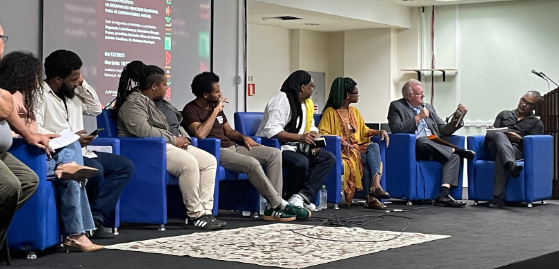 Na fotografia, veem-se várias pessoas negras sentadas umas ao lado das outras. Dentre elas, está...