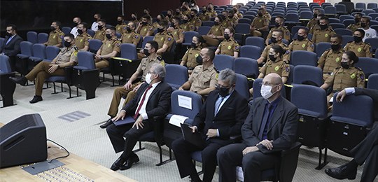 TRE-PR apresenta processo eleitoral para cadetes da Polícia Militar 1 Grupo de pessoas sentadas em um auditório. Três homens sentados à frente usam terno e, o restant...