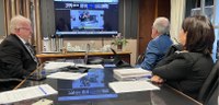 Fotografia em que aparece de lado o presidente Sigurd e de costas a diretora Solange e o secretá...