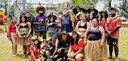 Fotografia de diversas pessoas indígenas, entre homens e mulheres, posando sorrindo ao redor de ...