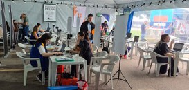 Fotografia de diversas pessoas com o colete amarelo e azul da Justiça Eleitoral realizando o ate...