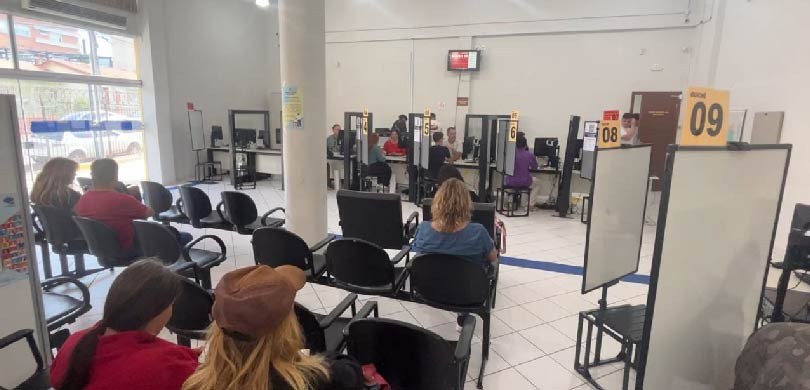 Fotografia de cinco pessoas, entre homens e mulheres, de costas sentadas em cadeiras pretas agua...