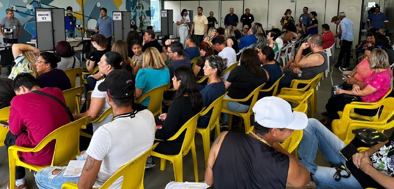 Fotografia de várias pessoas, entre homens e mulheres, sentadas em cadeiras amarelas de frente p...