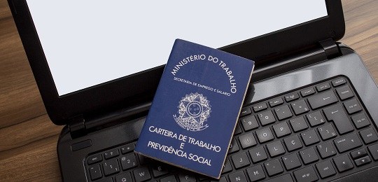 TRE-PR: carteira de trabalho uma carteira de trabalho sobre o teclado de um laptop