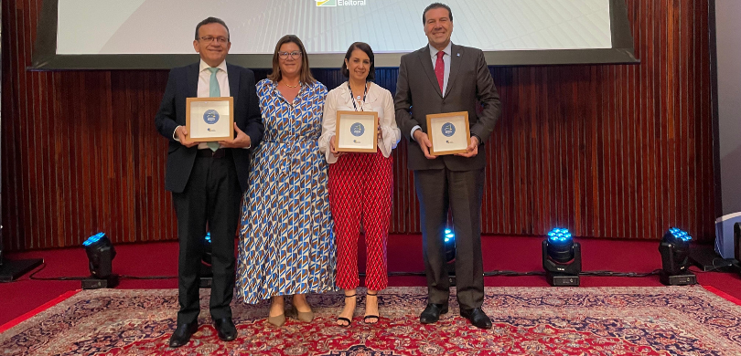 TRE-PR conquista a categoria diamante no Selo de Qualidade Eleitoral do TSE Fotografia de dois homens de terno e de duas mulheres com roupas formais estampadas nas cores az...