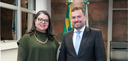 Fotografia na qual se observam um homem e uma mulher, em primeiro plano, posicionados lado a lad...