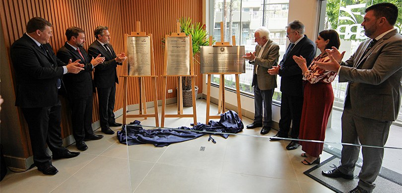 Fotografia de diversas pessoas, seis homens e uma mulher, em pé e distribuídos em dois grupos la...