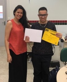 Igor Alves Palmeira recebendo o diploma padrão em amarelo, e o impresso em braille.