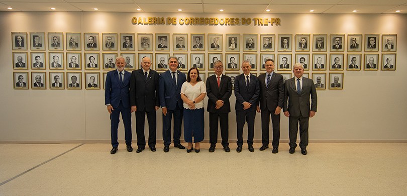 Fotografia em que se observa um grupo de oito pessoas, composto por sete homens e uma mulher, po...