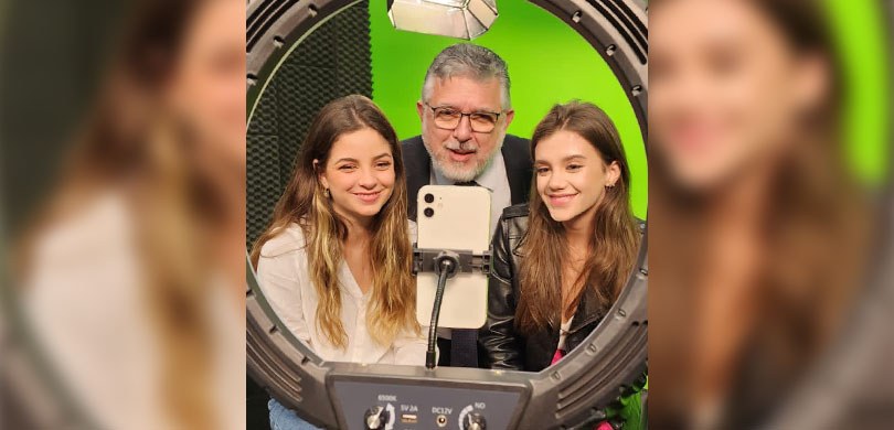 A foto mostra três pessoas sorrindo com um celular na frente, duas jovens e o presidente do Trib...