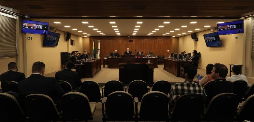 Fotografia dos membros da Corte na Sala de Sessões do TRE-PR. O local tem paredes amarelas, com ...