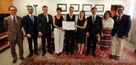 Fotografia que retrata um grupo de nove pessoas, composto por seis homens e três mulheres, posan...