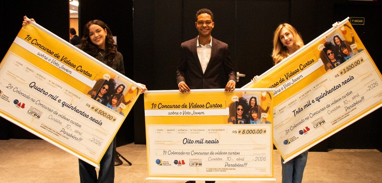 TRE-PR, OAB-PR e UFPR premiam vencedores do 1° Concurso de Vídeos Curtos sobre o Voto Jovem 2 Fotografia em que se observam três pessoas jovens, um homem e duas mulheres, posicionados lado a...