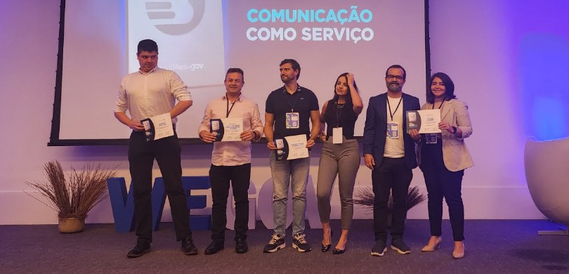 Foto em que aparecem quatro homens e duas mulheres perfilados e voltados para a câmera. Eles est...