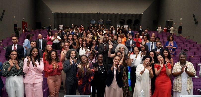 TRE-PR participa de encontro nacional de juízas e juízes negros em Brasília Na imagem, tirada do palco de um auditório, vêem-se na plateia várias pessoas, em sua maioria ne...