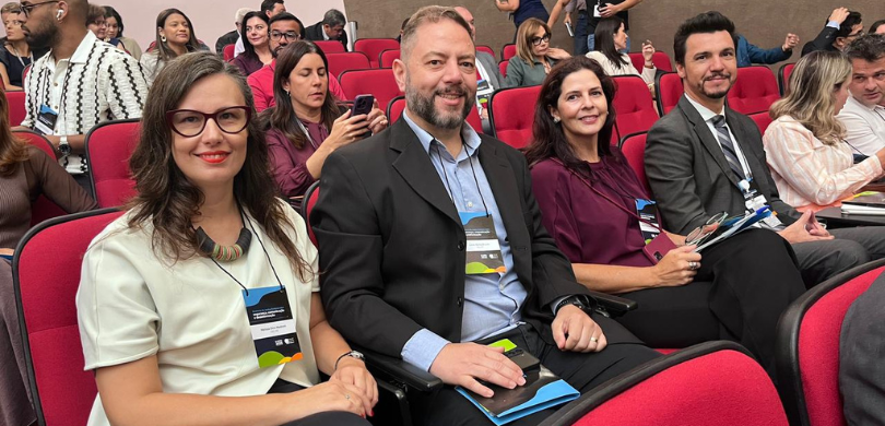 TRE-PR participa do seminário “Segurança, comunicação e desinformação” do TSE Fotografia que retrata um grupo de pessoas sentadas em um auditório com poltronas na cor vermelh...