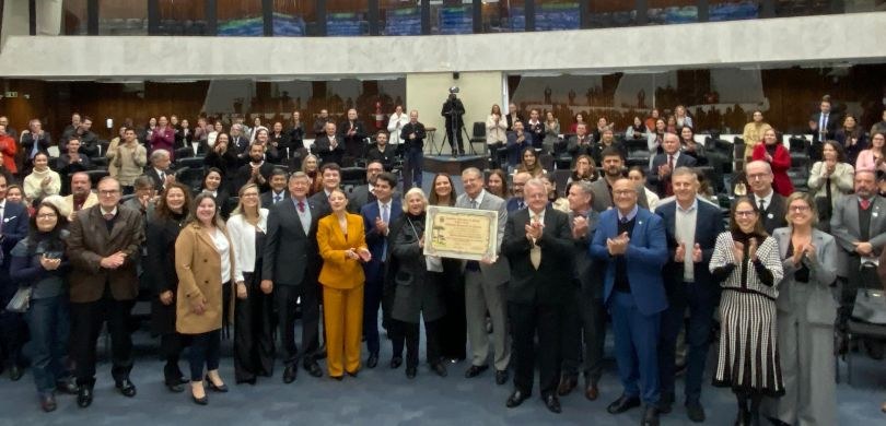 Fotografia em que aparecem várias pessoas posando no meio do plenário da Assembleia Legislativa ...