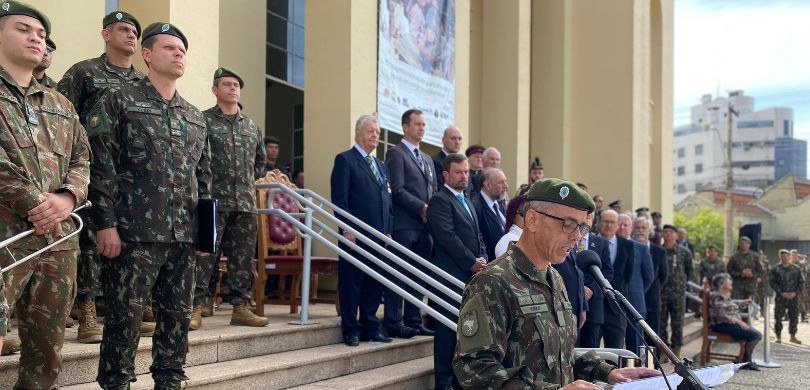 Fotografia em que aparece, em primeiro plano, um homem fardado falando em um púlpito nas escadar...