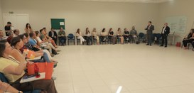 Fotografia de ambiente interno amplo com paredes e piso claros, onde diversas pessoas, entre hom...