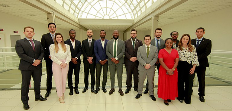 Fotografia que retrata um grupo de treze pessoas, composto por dez homens e três mulheres, posan...