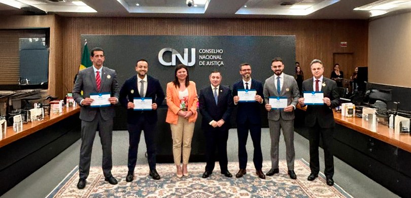 TRE-PR recebe o Selo Linguagem Simples Na fotografia, veem-se sete pessoas, uma mulher e seis homens, todos vestindo trajes sociais. A ...