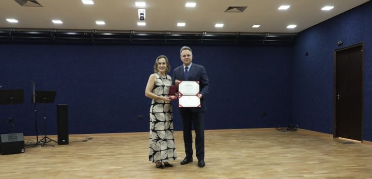 TRE-PR reinaugura auditório em solenidade com homenagens à embaixadora de acessibilidade Pietra Silvestri e ao Arquivo Público 4 Fotografia de um homem e uma mulher, ambos de pele clara, posando em pé ao centro de um auditóri...