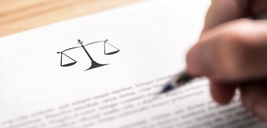 um papel com o símbolo da balança e um texto logo abaixo. uma caneta em cima do papel