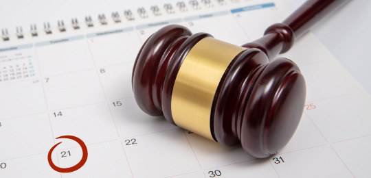 Imagem de um martelo de juíz e, embaixo, um calendário com o dia 21 circulado