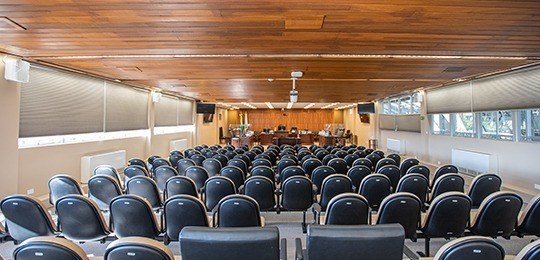 Fotografia da sala de sessões do TRE-PR vista do fundo. Em primeiro plano, há cadeiras.