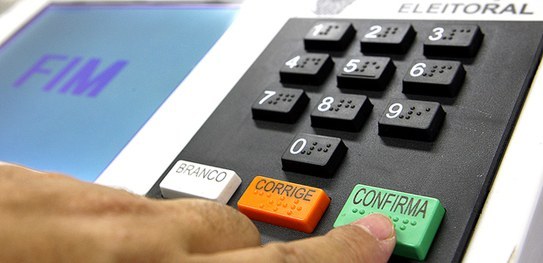 TRE-RS promove live "Urna Eletrônica: 25 Anos de Segurança, Transparência e Agilidade" Foto de uma mão apertando a tecla Confirma de uma urna eletrônica.