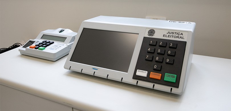 TSE abre inscrições para o Teste Público de Segurança do Sistema Eletrônico de Votação e de Apuração Fotografia de uma urna eletrônica em cima de um balcão branco.
