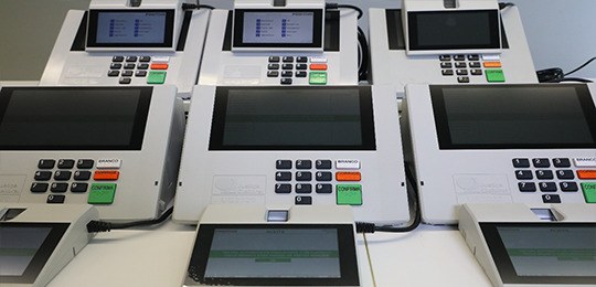 TSE apresenta novas urnas eletrônicas em Manaus (AM) Fotografia de seis novas urnas eletrônicas. Elas têm a tela posicionada em cima do teclado numér...