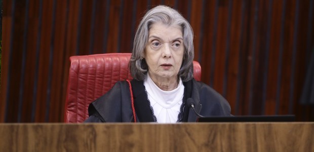 Fotografia em que se vê a ministra Cármen Lúcia sentada atrás de uma mesa de um plenário.
