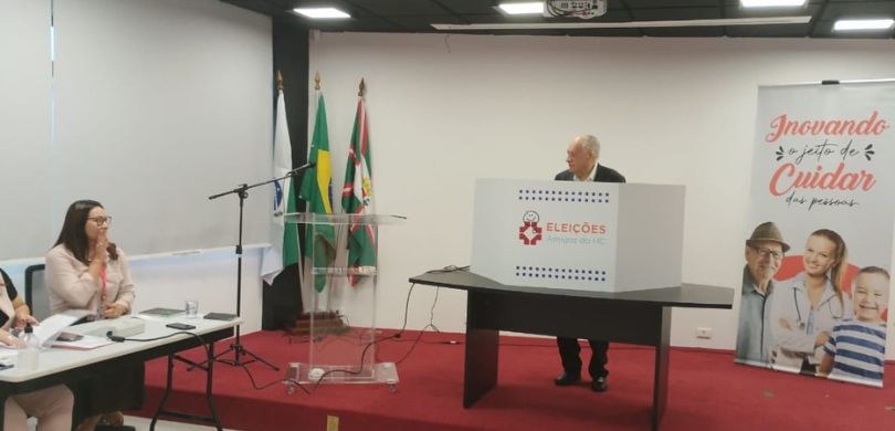 Urnas do TRE-PR são usadas em eleição da Associação Amigos do HC Fotografia, na qual é possível ver em cima de um palco vermelho, um homem realizando seu voto em...