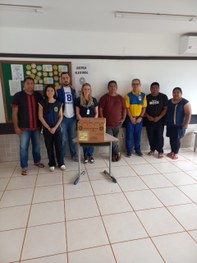 Fotografia em ambiente externo na qual se observam cinco pessoas de peles claras posando sorride...