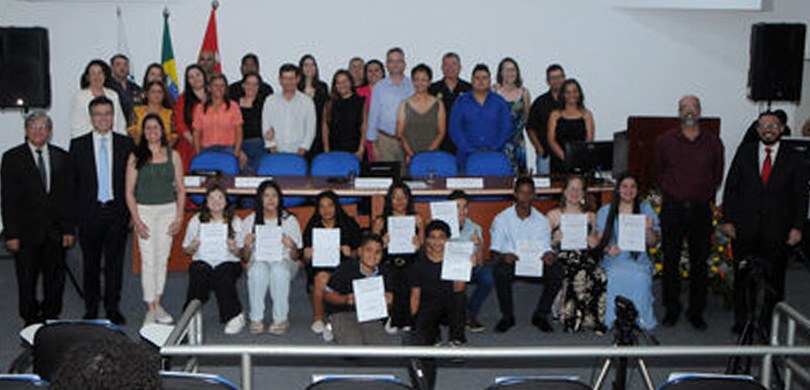 Fotografia de várias pessoas, entre adultos e adolescentes, posando sorrindo na Câmara Municipal...