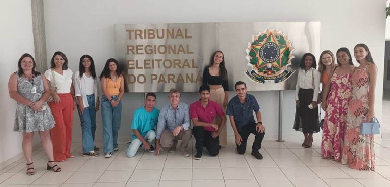 Vereadores mirins visitam a sede do TRE-PR 2 Fotografia de nove mulheres e quatro homens, entre adultos e adolescentes, posando sorrindo ao r...
